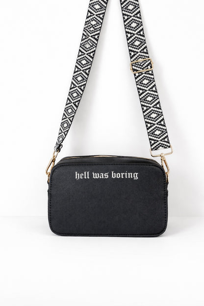 Schwarze Crossbody Umhängetasche für Damen mit Aufdruck „hell was boring“ und gemustertem Taschengurt.