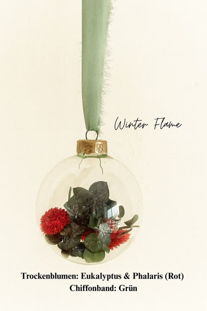 Personalisierte Weihnachtskugel aus Glas mit goldenem Kranz und grünen Chiffon-Aufhänger, gefüllt mit roten Phalaris-Trockenblumen und grünem Eukalyptus, Variante ‚Winter Flame‘.