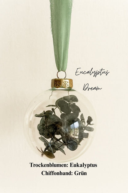 Personalisierte Weihnachtskugel aus Glas mit goldenem Kranz und grünen Chiffon-Aufhänger, gefüllt mit Eukalyptus-Trockenblättern, Variante ‚Eucalyptus Dream‘.
