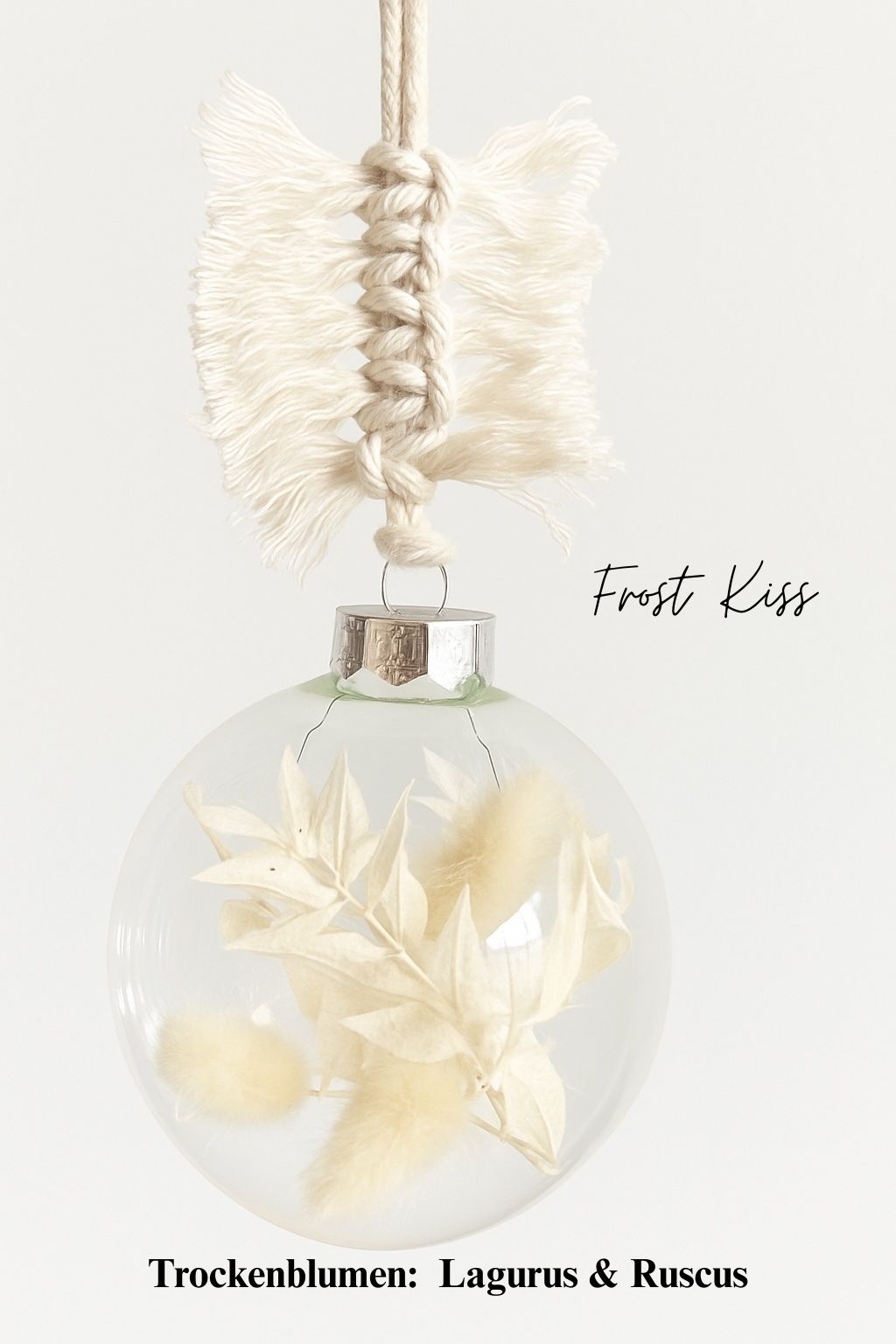 Personalisierte Weihnachtskugel aus Glas mit silbernem Kranz und handgemachtem Makramee-Aufhänger, gefüllt mit weißen Trockenblumen Lagurus und Ruscus, Variante ‚Frost Kiss‘.