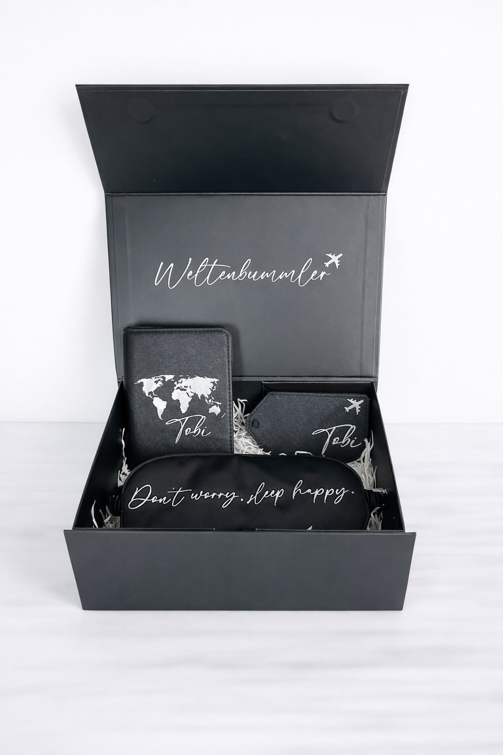 Schwarze Weltenbummler Geschenkbox mit personalisierter Passhülle, Kofferanhänger und Schlafmaske