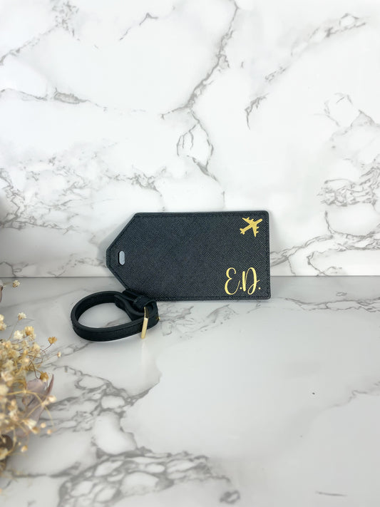 Personalisierter Kofferanhänger in Schwarz mit goldenen Initialen und Flugzeugsymbol, veganes Leder – stilvolles Reiseaccessoire oder Geschenkidee.