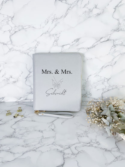 Personalisierter Dokumentenorganizer in Hellgrau mit Aufdruck „Mrs. & Mrs.“ zur Aufbewahrung von Reise- und Hochzeitsunterlagen.