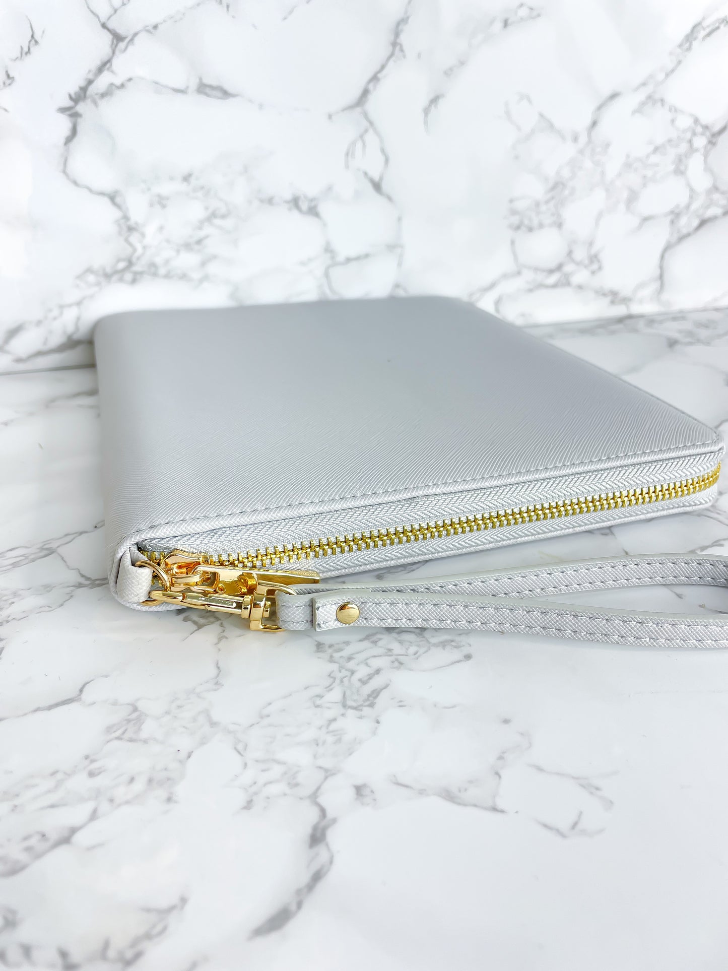 Goldfarbener Reißverschluss an einem grauen Dokumentenorganizer für Reiseunterlagen.