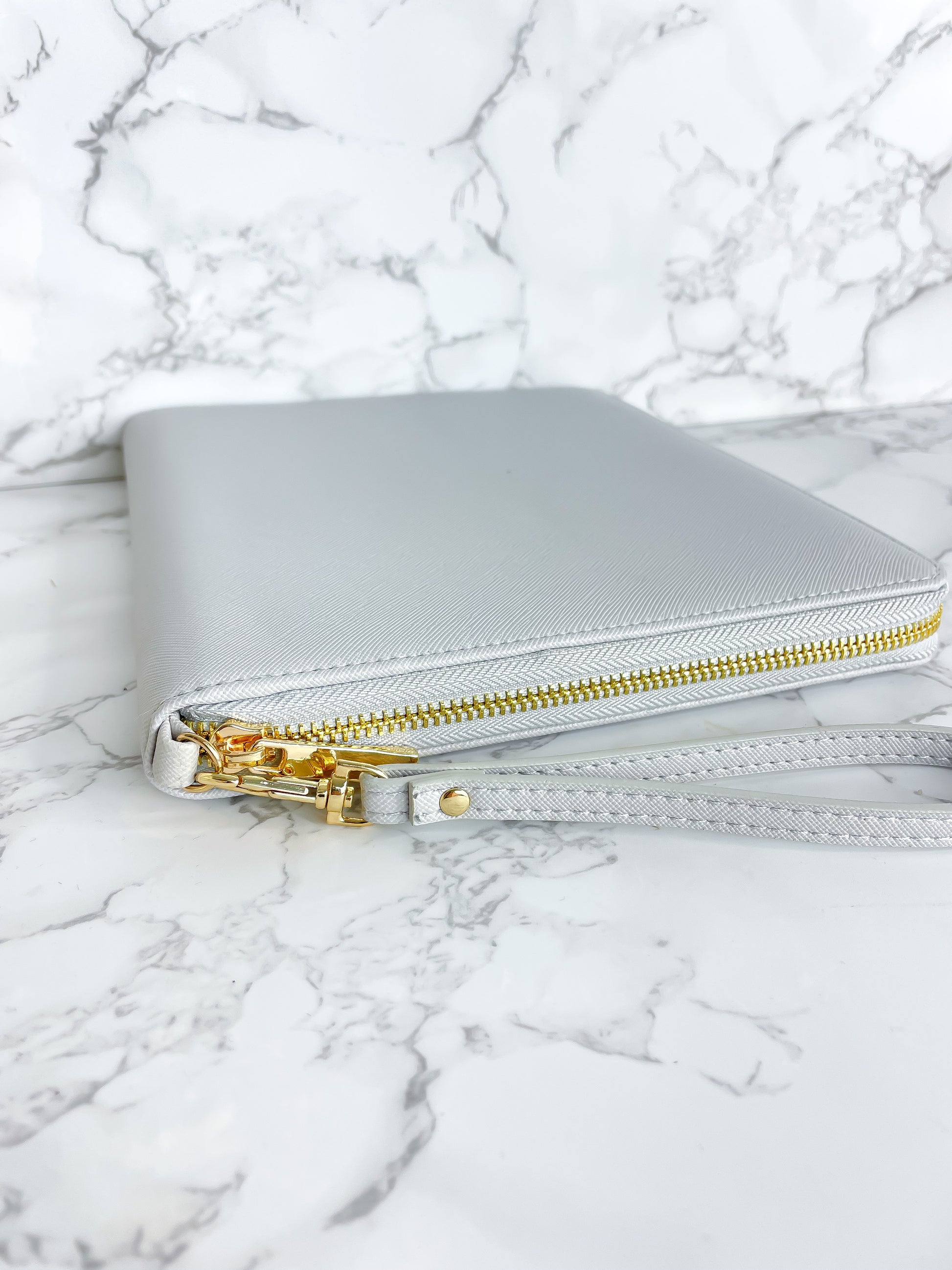 Goldfarbener Reißverschluss an einem grauen Dokumentenorganizer für Reiseunterlagen.