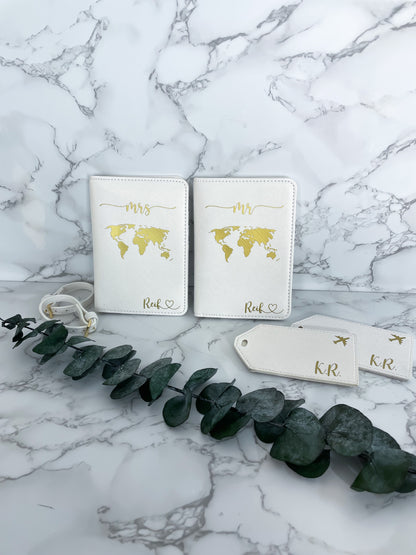 Personalisierte Reisepasshüllen Mr & Mrs in Weiß mit goldener Weltkarte und Kofferanhängern – elegantes Hochzeitsgeschenk aus veganem Leder.
